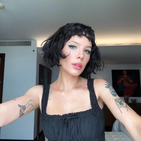 Halsey is taking a selfie in her room wearing a black dress.